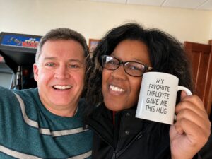 Two Lanex team members smiling together in the office while holding a humorous coffee mug, reflecting the company's friendly workplace culture.